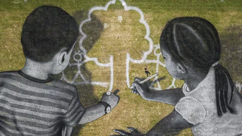 Artist Saype poses with his land art painting at UN Headquarters, Geneva, Switzerland (© Valentin Flauraud/EPA-EFE/Shutterstock)