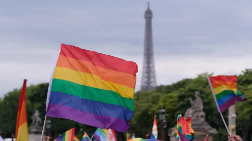 Drapeau arc-en-ciel brandi devant la tour Eiffel lors de la marche des fiertés (© Yuriko Nakao/Getty Images)