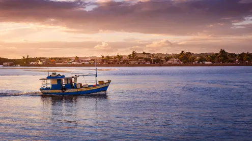 Barco de pescadores flutuando em um rio durante o pôr do sol (© agustavop/iStock/Getty Images Plus)
